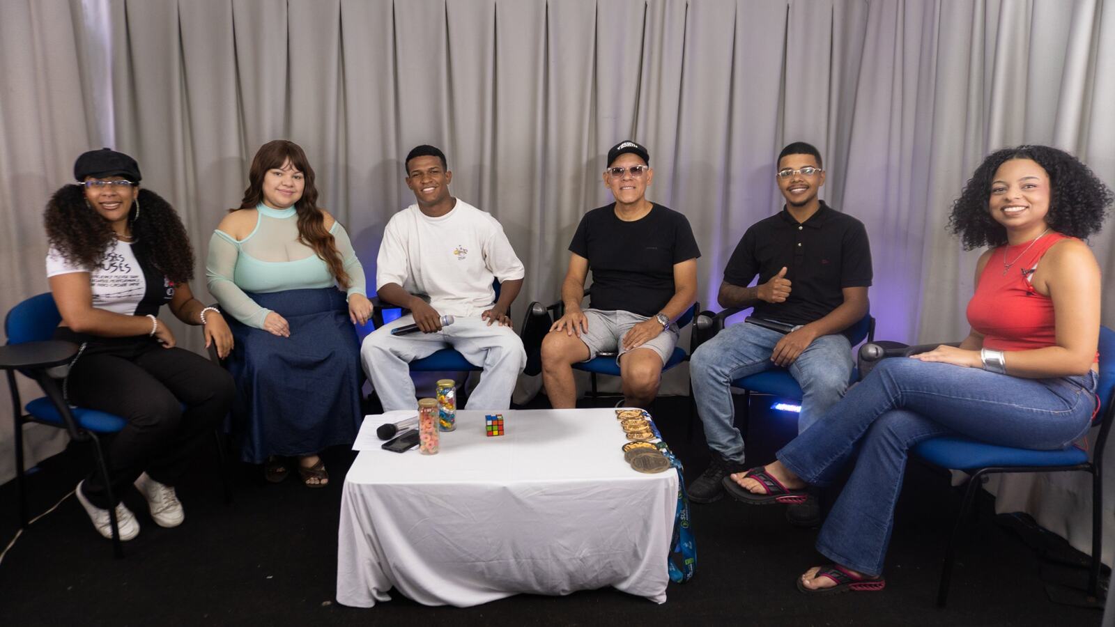 Participantes e convidados reunidos no estúdio, sorrindo para a câmera